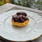 Chocolate-glazed pastry on a decorative plate with a blurred natural background